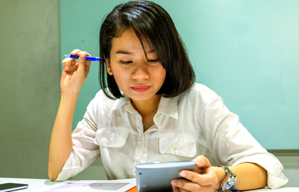 young woman sits at a table looking at a piece of paper